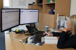 Woman working at computer and taking notes