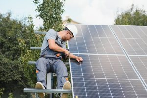 Man in a protective helmet working on solar panels
