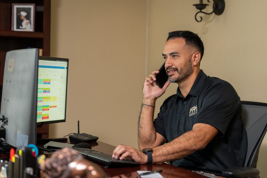 Merit Facility Management team member on the phone and working on computer