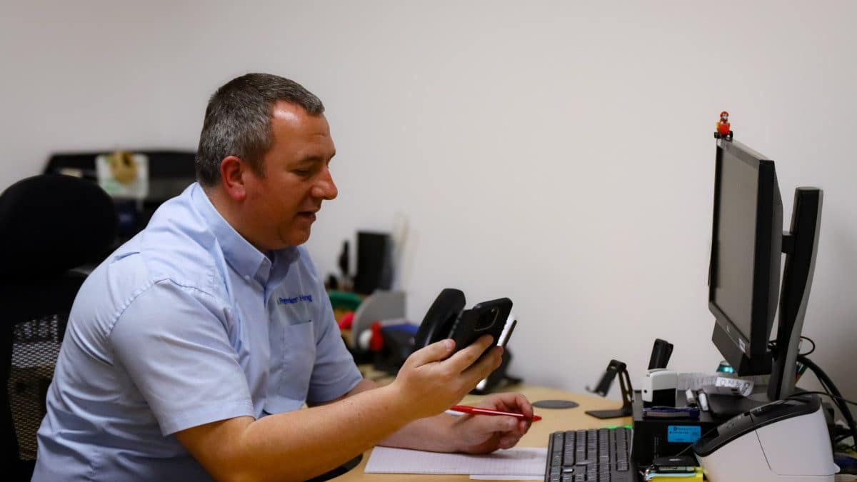 Man holding phone and working at computer in an office.