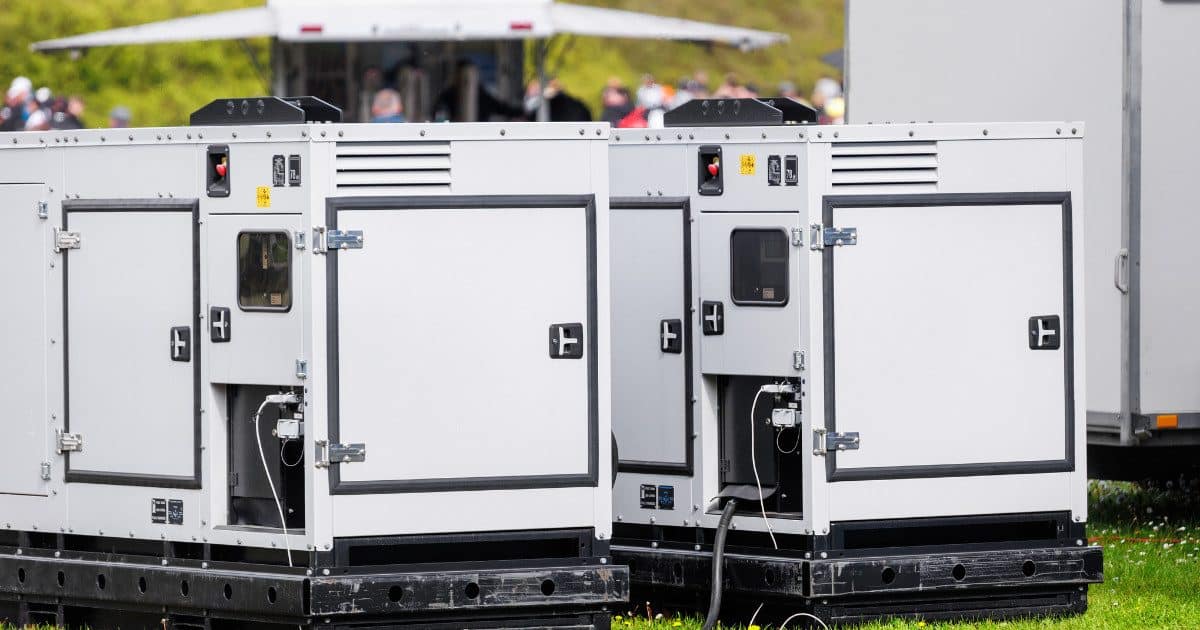 Two white generators outside on grass