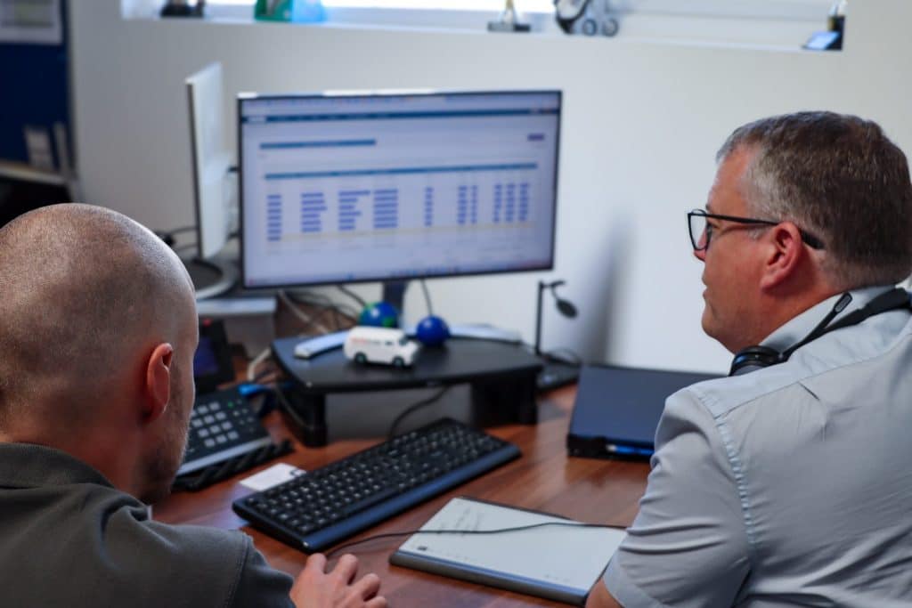 Two workers looking at Commusoft app on desktop