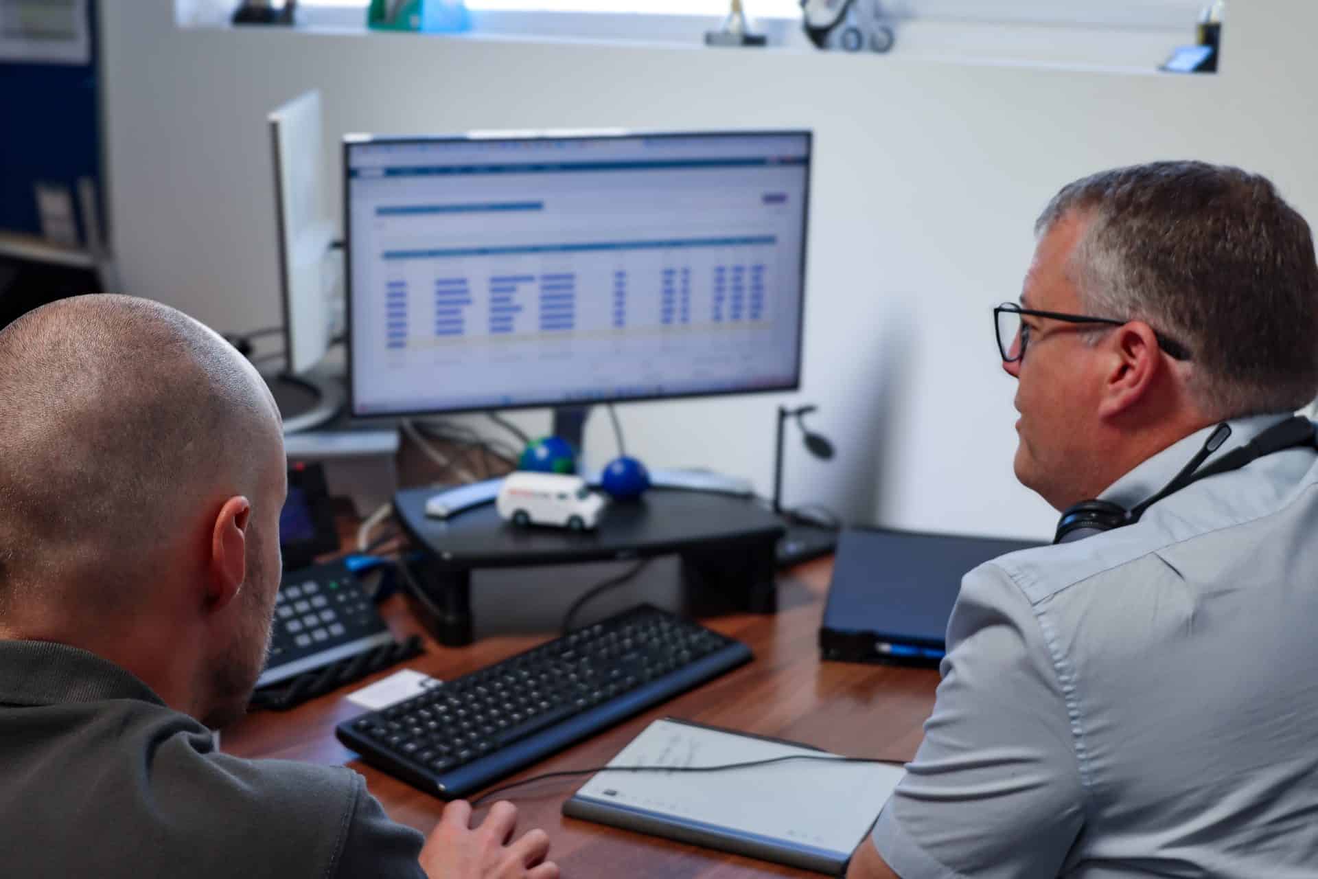 Two workers looking at Commusoft app on desktop